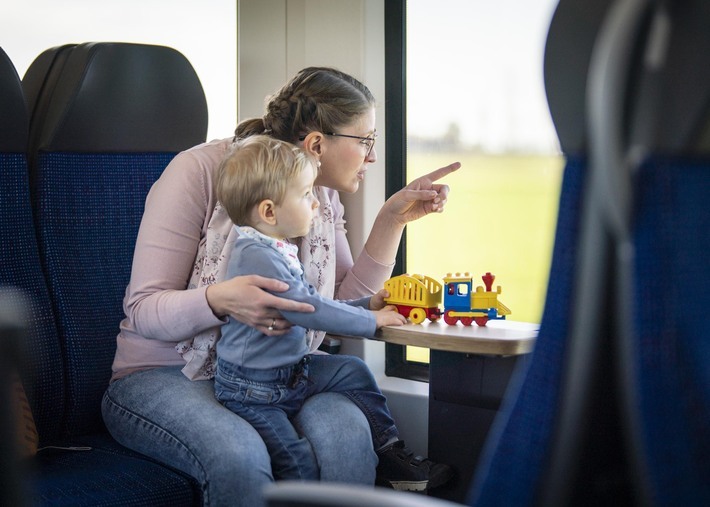 Eine Frau sitzt mit Ihrem Kleinkind im Zug und sieht aus dem Fenster.