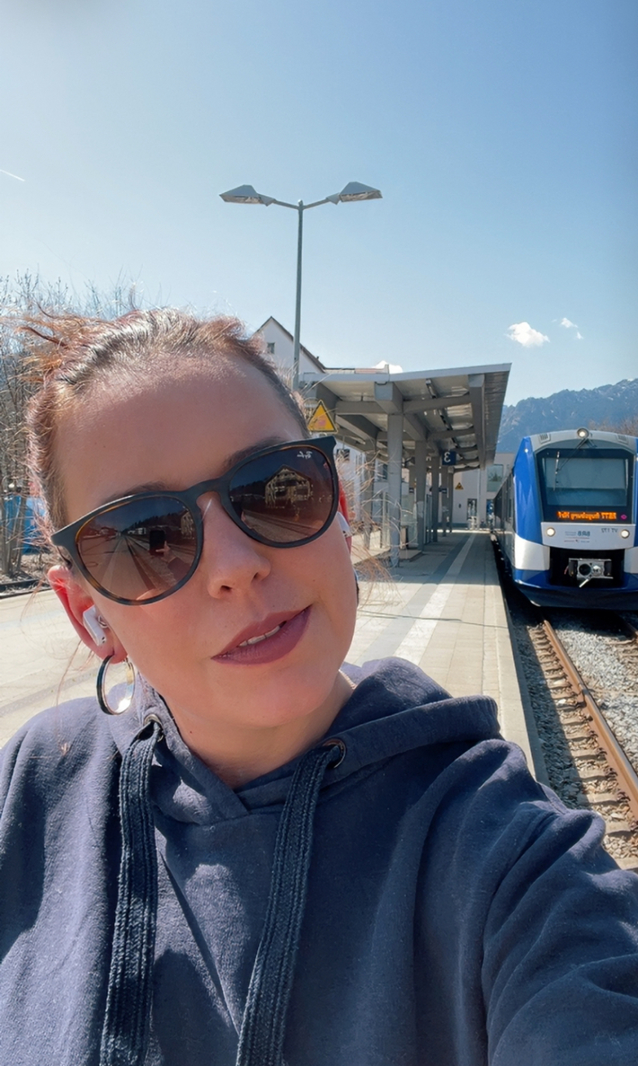 Natalie Mangold steht am Bahngleis vor einem BRB Zug.