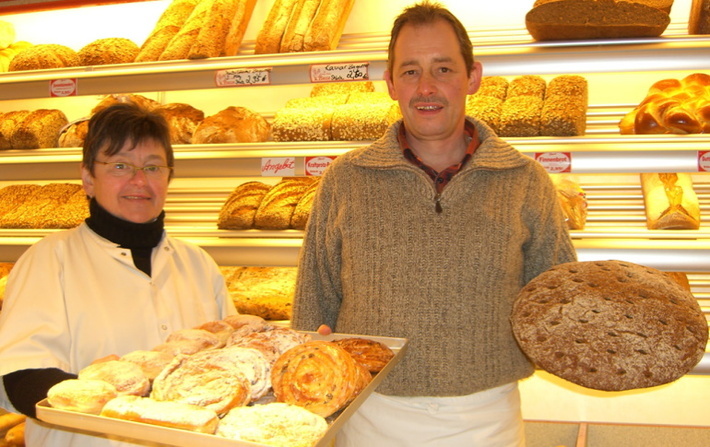 Brot- und Kuchenstand auf dem Wochenmarkt mit Verkäufer*in