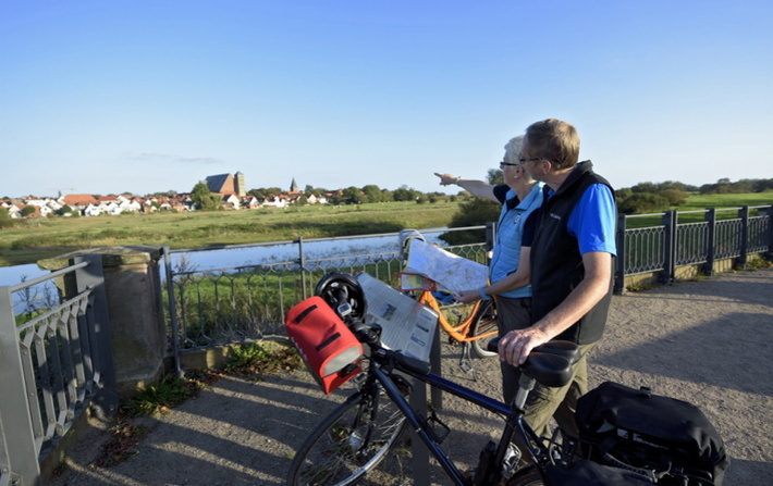 Radfahrer mit informieren sich mit Karte an der Aller