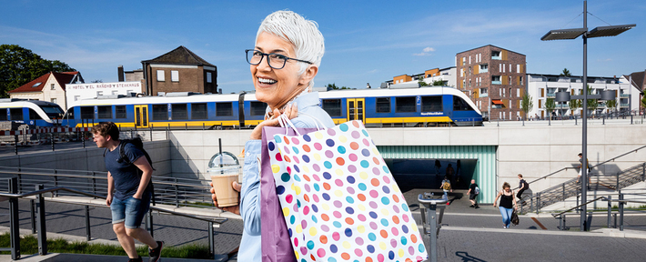 Frau mit Einkaufstüten mit Bahnhof im Hintergrund