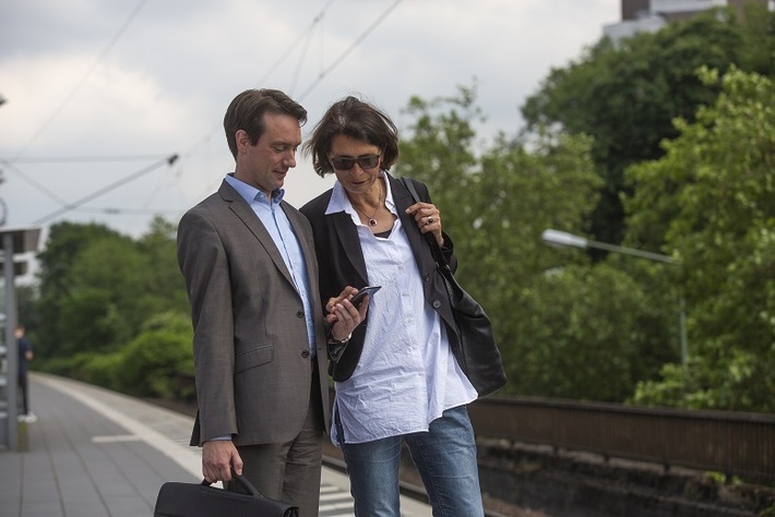 Eine Frau und ein Mann informieren sich am  Bahnsteig über die nächsten Zugverbindungen. 