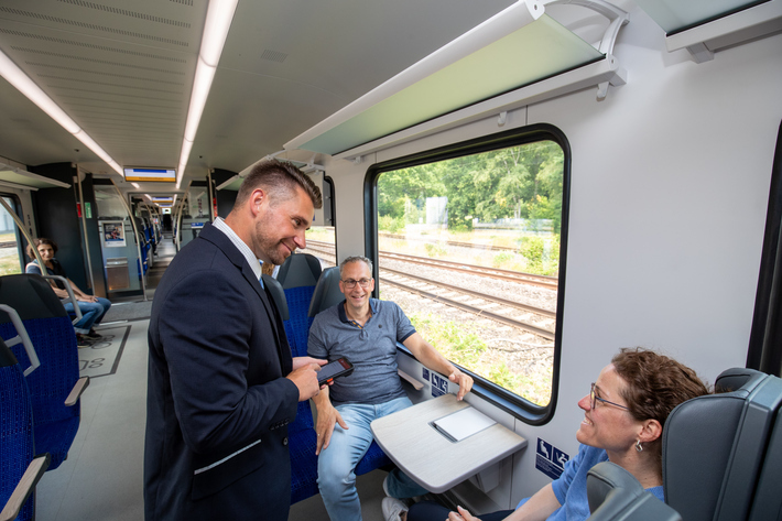 Kundenbetreuer:innen im Zug der NordWestBahn mit Fahrgästen