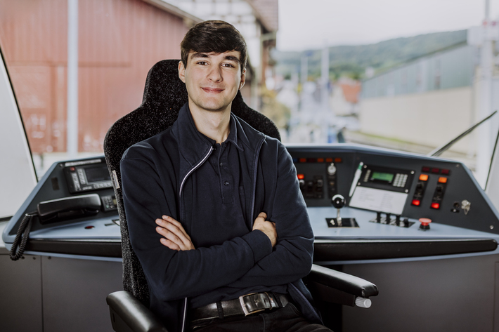 Lokführer im Führerstand guckt in die Kamera mit verschränkten Armen.