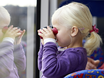 Kind schaut mit Fernglas aus Bus